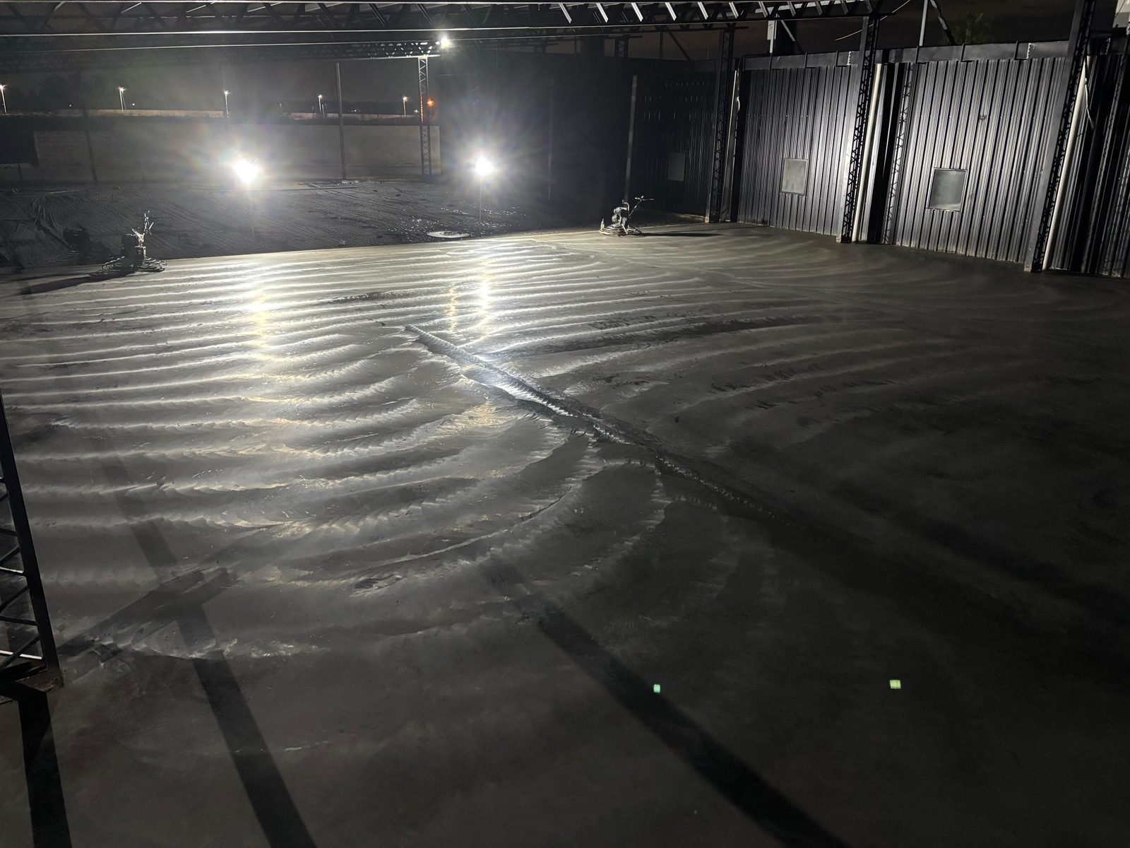 Piso de hormigón siendo terminado con alisadoras de noche